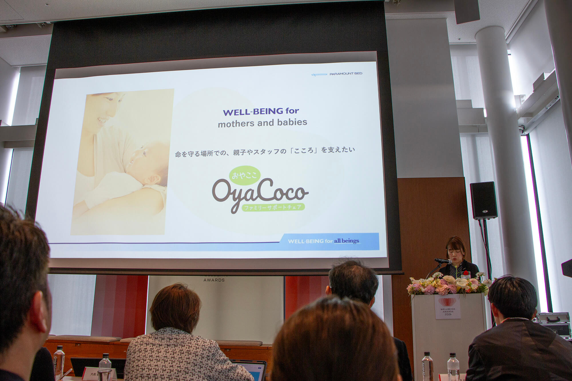 パラマウントベッド株式会社 Tsubaki Project（ツバキプロジェクト）のプレゼンテーション。スクリーンに「WELL-BEING for mothers and babies」と「OyaCoco（オヤココ）」の文字