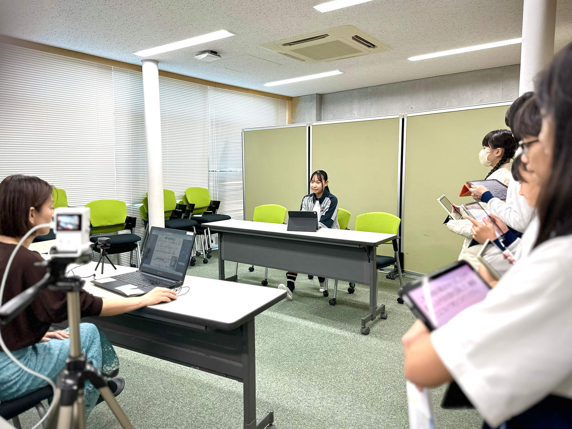 配信風景。ディレクターの先生のキュー出しで発表をする保健安全委員と、次の発表のために待機する児童たち