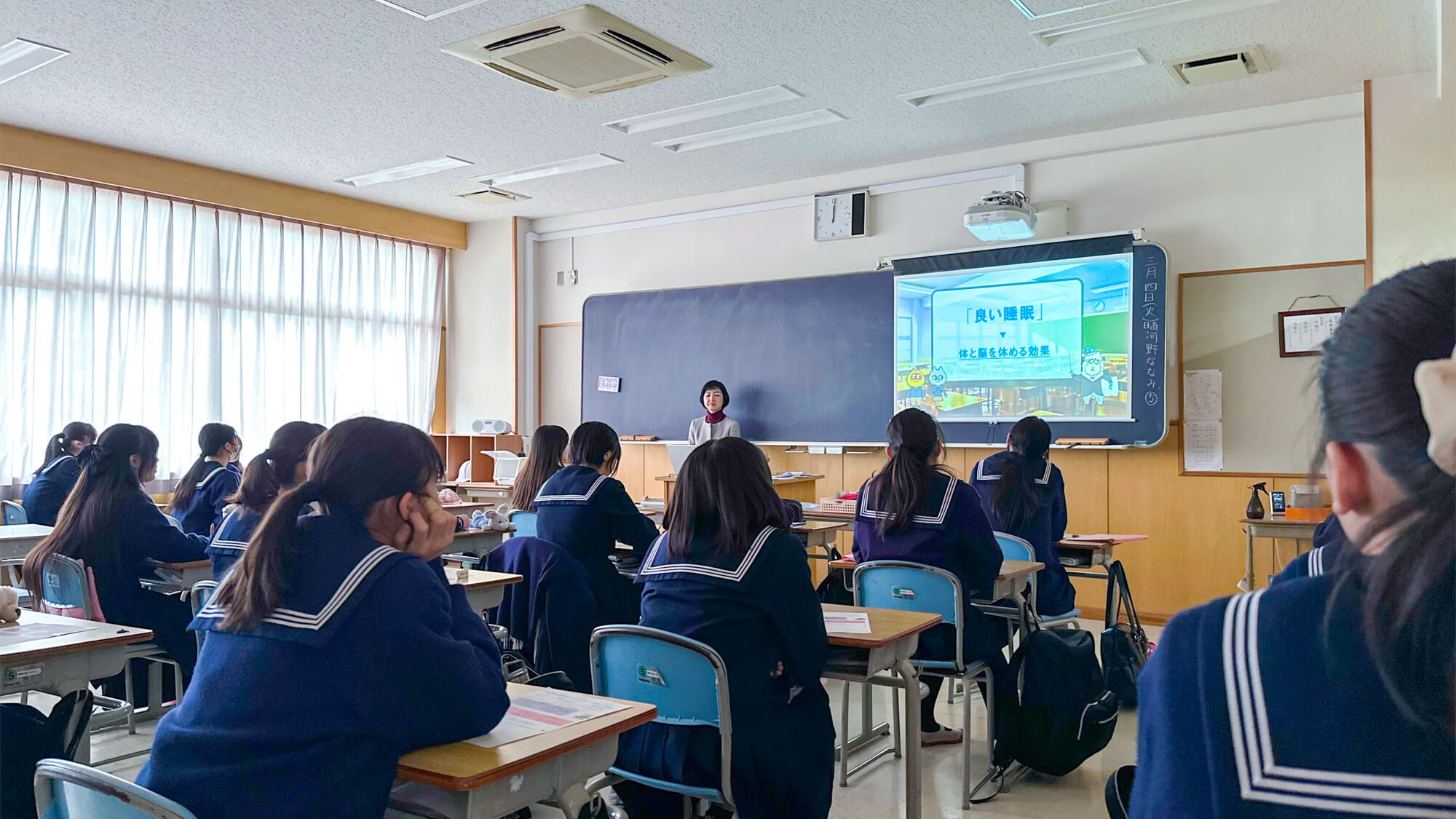 教材のひとつ、スライドを使って授業を行う堤真美先生とそれを聞き入る生徒たち