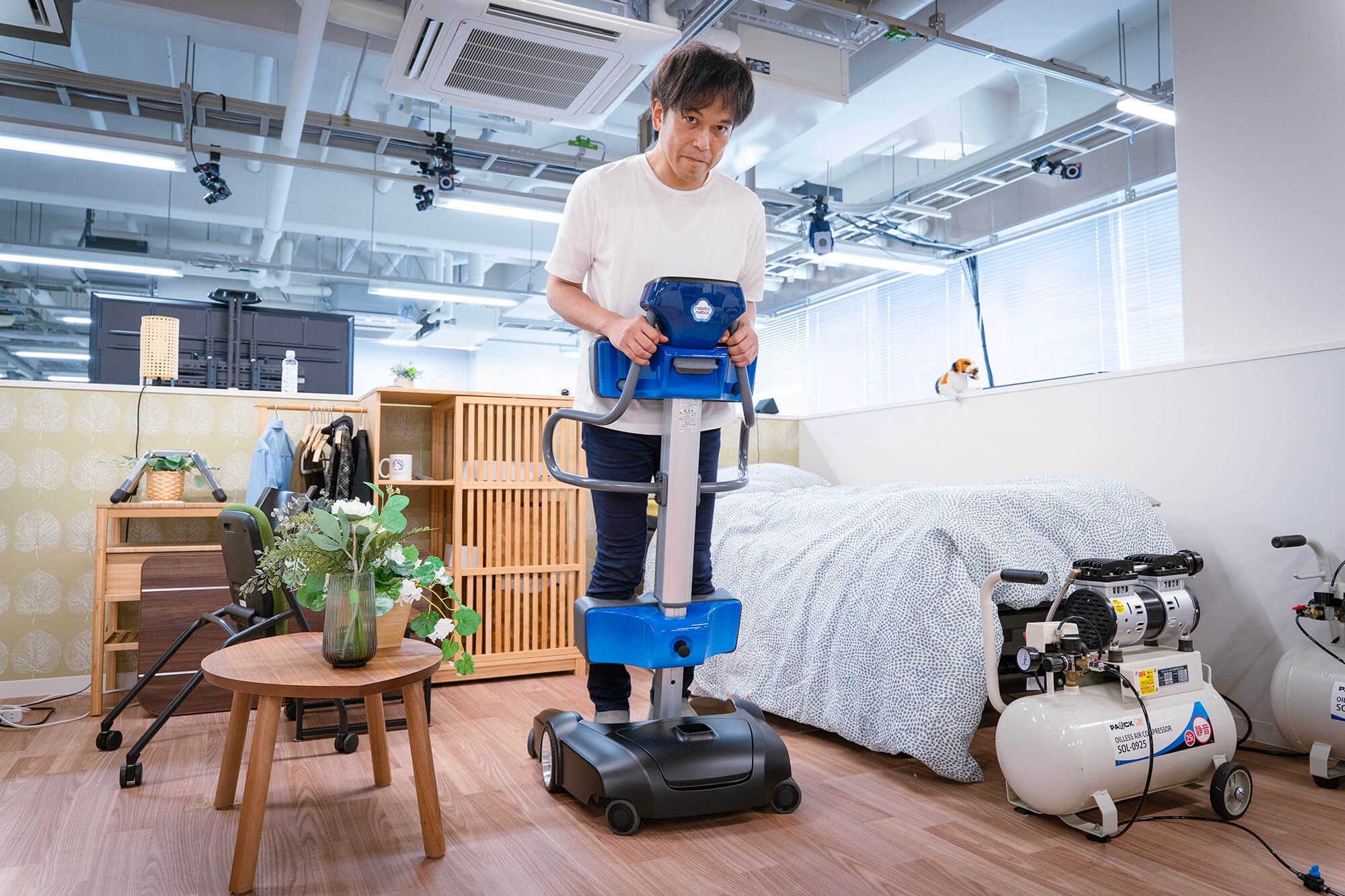 家具や日用品が配置された部屋で、移動支援ロボットに乗る初雁（はつかり）さん