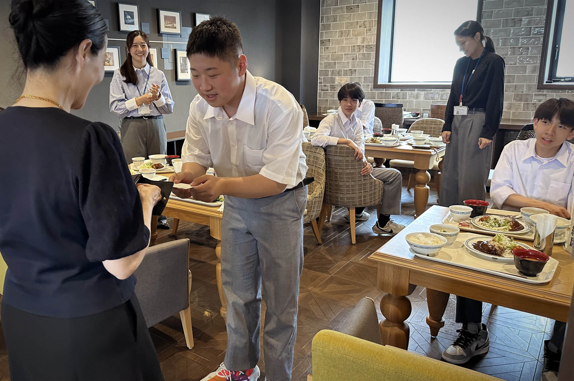 社員食堂で名刺交換をする、長橋中学校生徒とパラマウントベッド社員