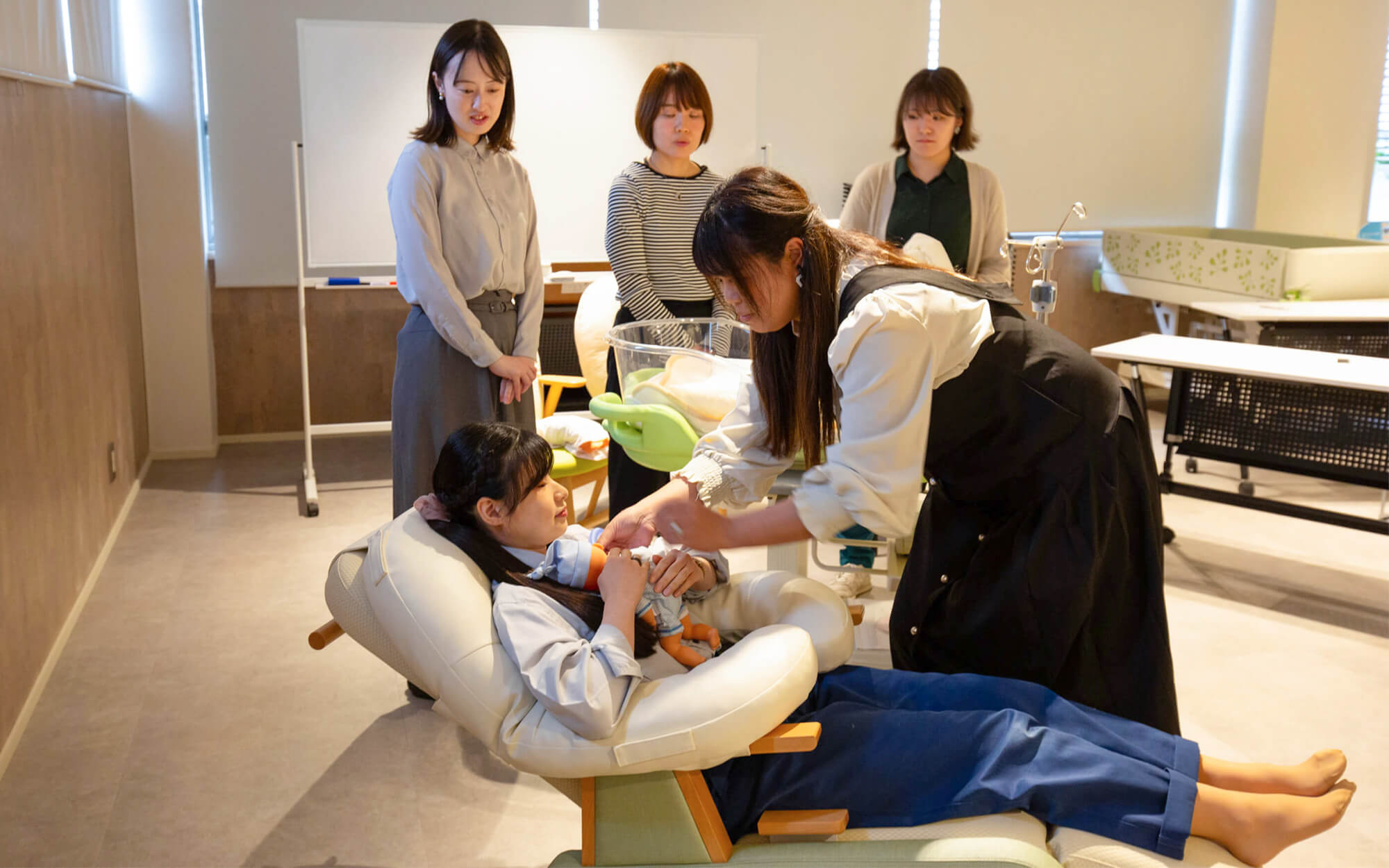 低出生体重児を模した人形を抱き、カンガルーケアをするお母さんの様子を再現するTsubaki Project(ツバキプロジェクト)メンバー